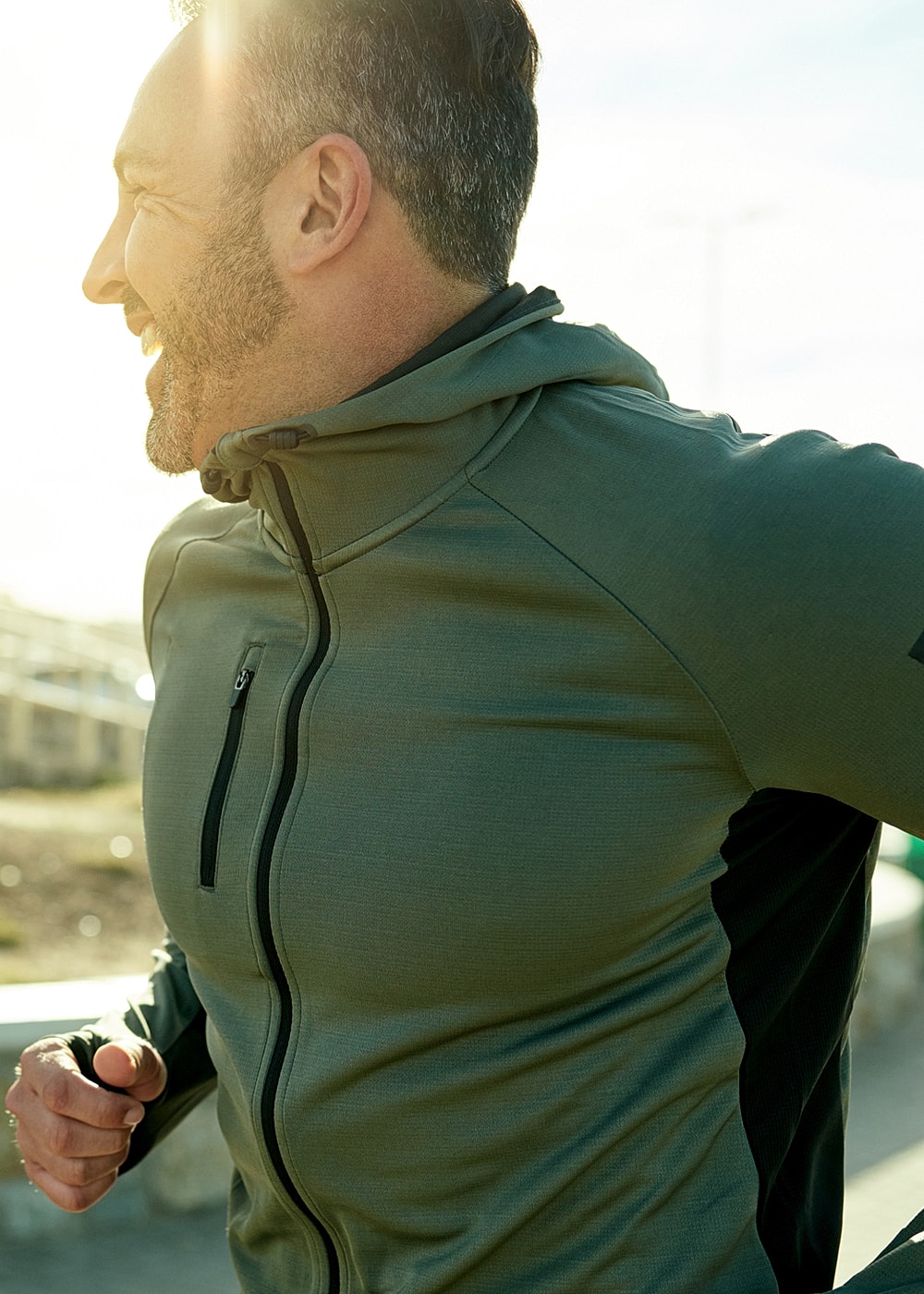Man running in athletic wear, smiling outdoors.